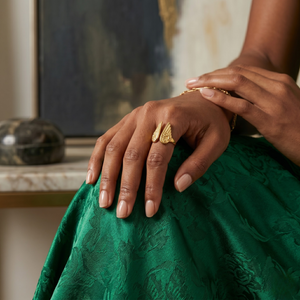 Yellow gold feather band on woman's hand, wearing green dress, elegant and stylish jewelry accessory