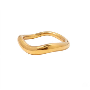 Gold wave-shaped ring with a smooth, flowing design on a white background