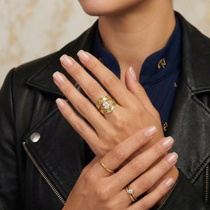 Model wearing Paragon Teardrop Ring in gold with gemstone accents, paired with additional gold rings, leather jacket