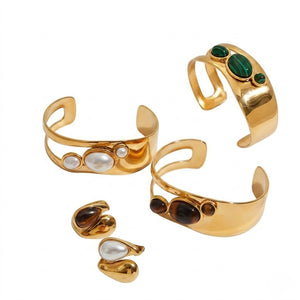 Gold cuff bracelets with earth-tone gemstones and matching earrings on a white background.