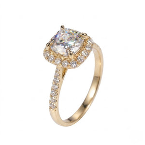 Gold ring featuring a cushion-cut cubic Moissanite center stone surrounded by a halo of round accents shown at an angle on a plain white background by J.Collins