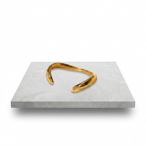 Gold luxury plated cuff bracelet on a white surface, sleek curved design