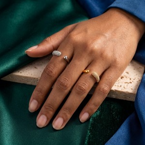 Hand wearing gold and silver curved pavé rings on green velvet background