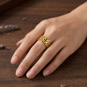 Gold woven brick ring on hand resting on wood surface with lavender sprigs nearby