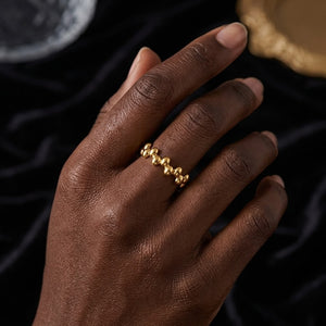 Oracle Beaded Ring in gold on hand with black velvet background, elegant and modern style