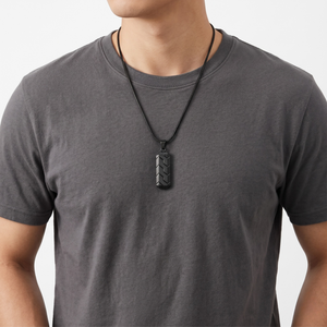 Man wearing a gray t-shirt with a Unique Black Pendant necklace on a leather cord from J.Collins Jewelry.