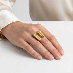 Twin Bar Ring in gold on a person's hand with a white sleeve background