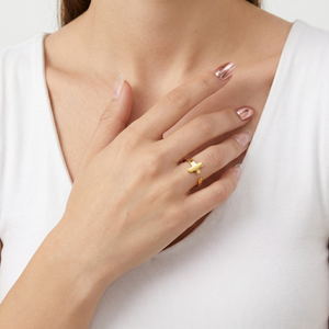 Gold Whisper Ring on model's finger, modern minimal design, worn with white top, hand touching chest