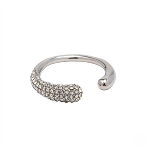 Curved silver pavé ring with clear crystals on one end against a white background