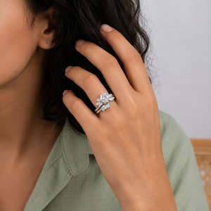 Sterling silver ring featuring a round center cubic Moissanite stone flanked by marquise accents worn on finger by model Wearing a sage green shirt by J.Collins