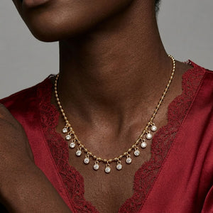 Model Tiffany wearing a gold bead chain fringe necklace with dangling bezel-set round diamond charms paired with a red lace top | J.Collins Jewelry