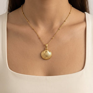 Model wearing a gold ocean-inspired seashell pendant necklace paired with a cream square-neck top | J.Collins Jewelry