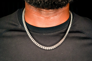 Person wearing a silver chain necklace against a black background