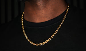 Gold chain necklace on a person wearing a black shirt against a dark background-Essential-Rope-Chain-JCollins-Jewelry