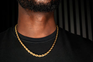 Gold chain necklace on a person wearing a black shirt against a dark background-J.Collins Jewelry