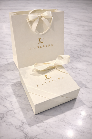 J. Collins jewelry box with bow on a marble surface