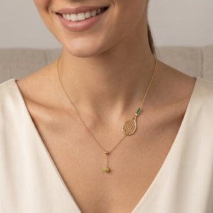 Model Tiffany wearing a whimsical gold tennis racket and ball charm necklace paired with a white V-neck top | J.Collins Jewelry
