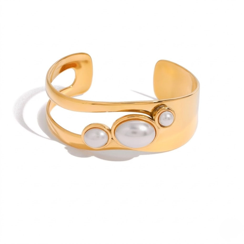 Gold cuff bracelet with three oval pearls on top, open-ended contemporary design.
