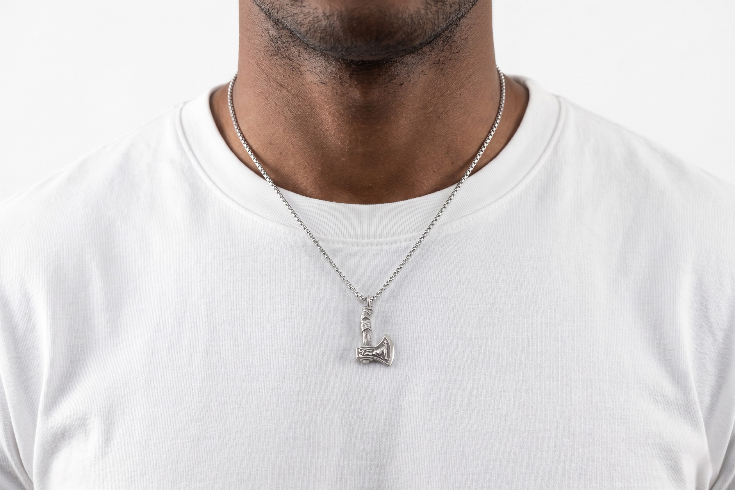 Man wearing a white t-shirt and necklace with a small pendant on a plain background- J.Collins Jewelry