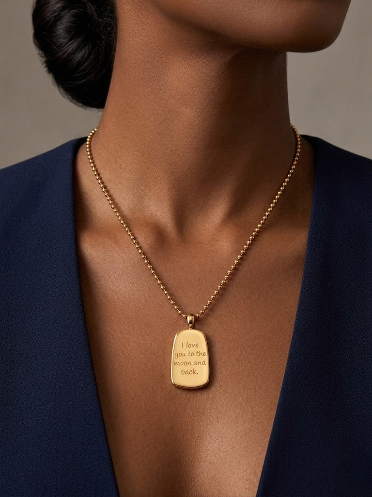Gold medallion necklace engraved with "I love you to the moon and back" on model wearing blue attire
