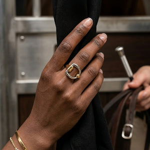 Hand wearing a two-tone gold and silver Curb Buckle Ring holding a black cloth in a lifestyle setting