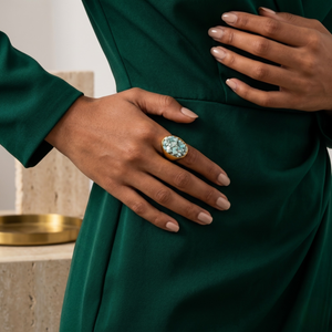 Woman wearing green dress with gold ring featuring blue quartz on her hand.