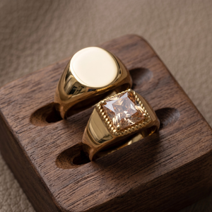 Gold essential signet band rings with smooth and square gemstone styles on a wooden display stand