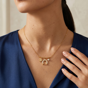 Gold clover and horseshoe pendant necklace worn by model in blue blouse, elegant and delicate design