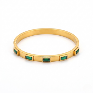 Gold bangle with rectangular emerald stones inlay design on a white background