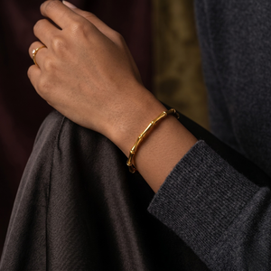Sculpted Bamboo Bracelet in gold on wrist, paired with subtle gold ring, casual lifestyle setting.