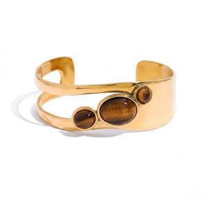 Gold cuff bracelet with three brown stones on a smooth band