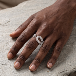 Diamond-encrusted Celestial Sparkle ring on a hand, displayed on a textured stone surface.
