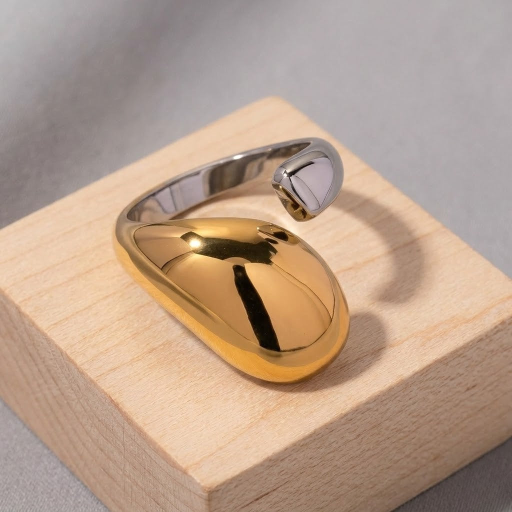 Vesper Duo Ring, sleek silver and gold two-tone metal band displayed on a light wood block