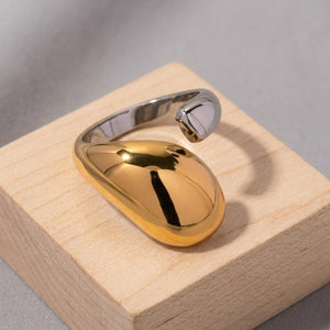 Vesper Duo Ring, sleek silver and gold two-tone metal band displayed on a light wood block