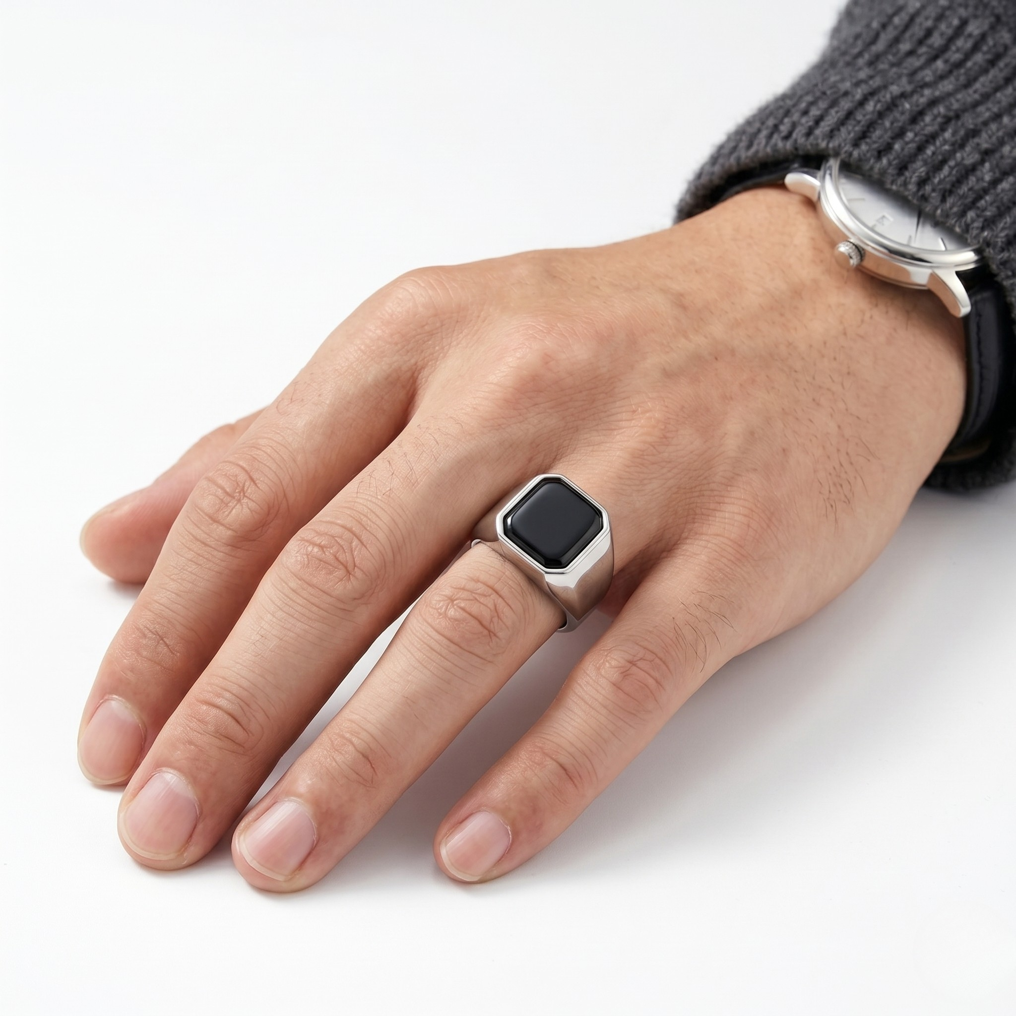 Hand wearing silver onyx signet ring with a sweater and watch background