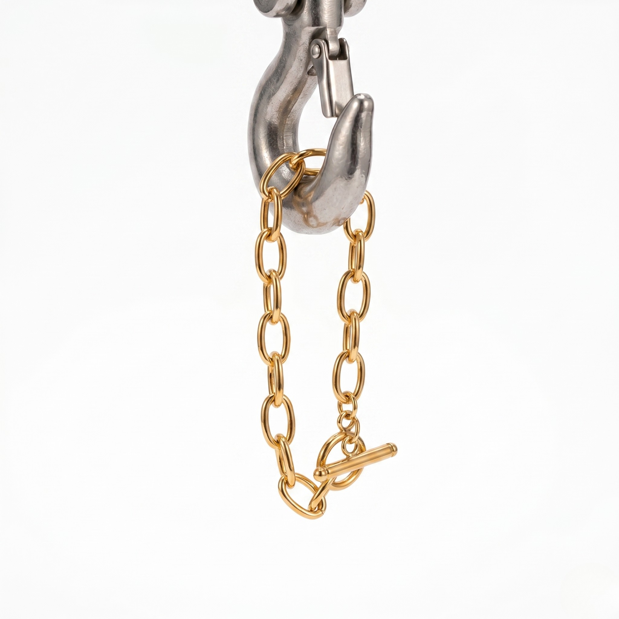 Gold-plated chain bangle with toggle clasp, hanging on a metallic hook