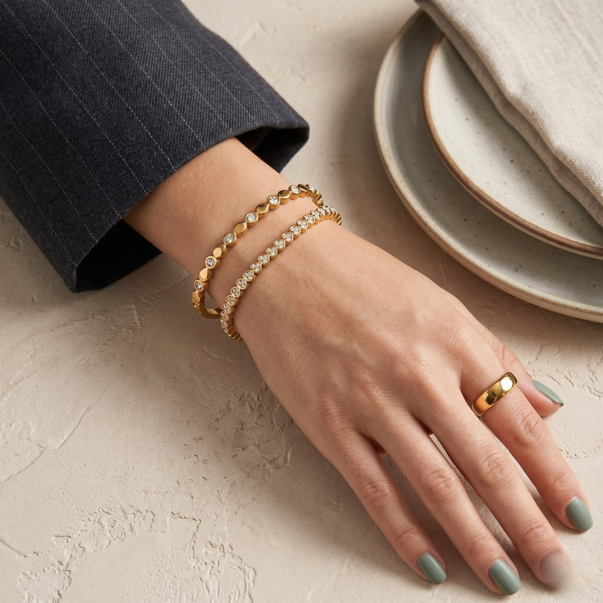 Gold link bangle on wrist with two additional bracelets, showcasing modern style and fashion jewelry context