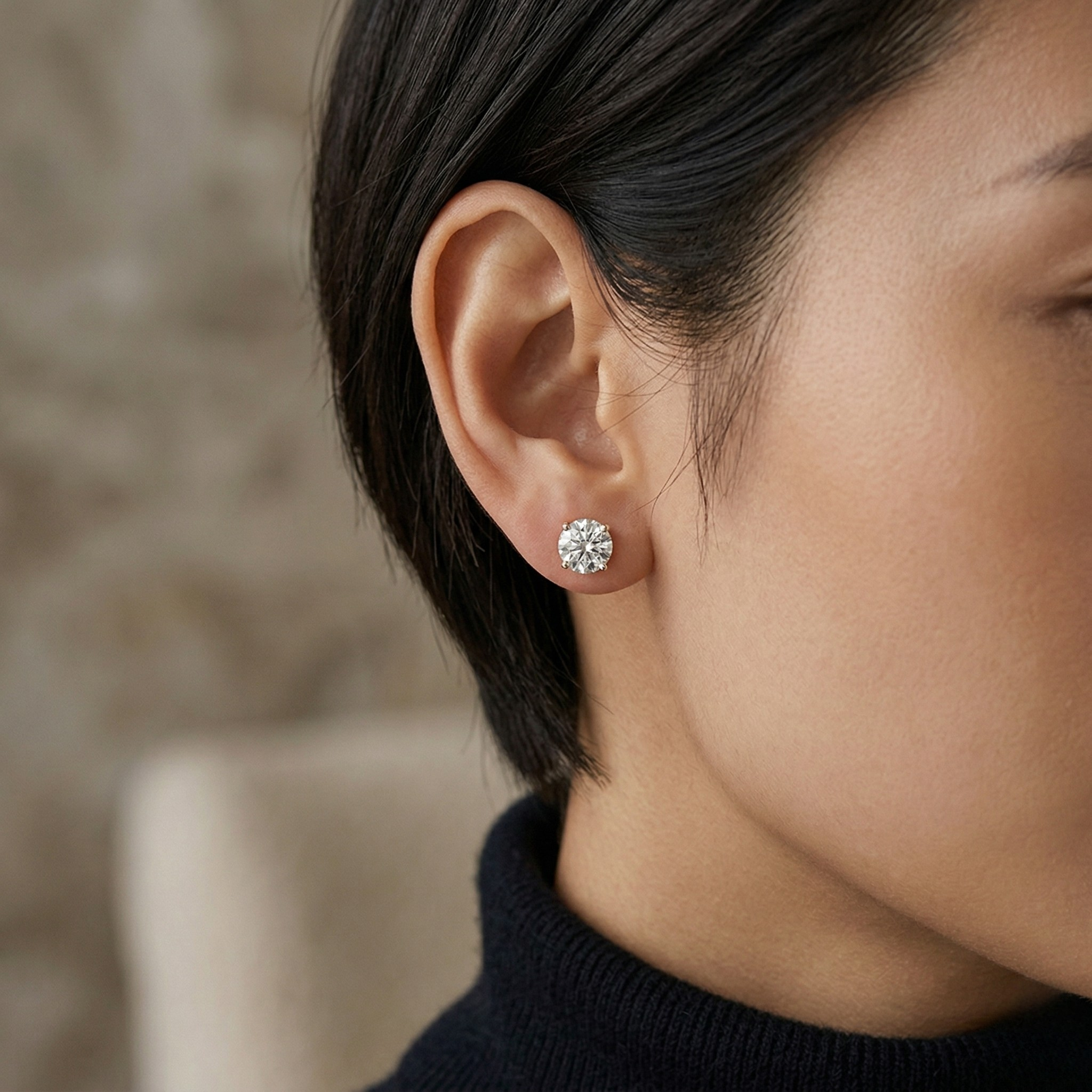 Close-up of a person wearing a diamond earring with a blurred background - 10K Yellow Gold Lab Diamond Earrings Basket 1.1ct - J. Collins Jewelry 