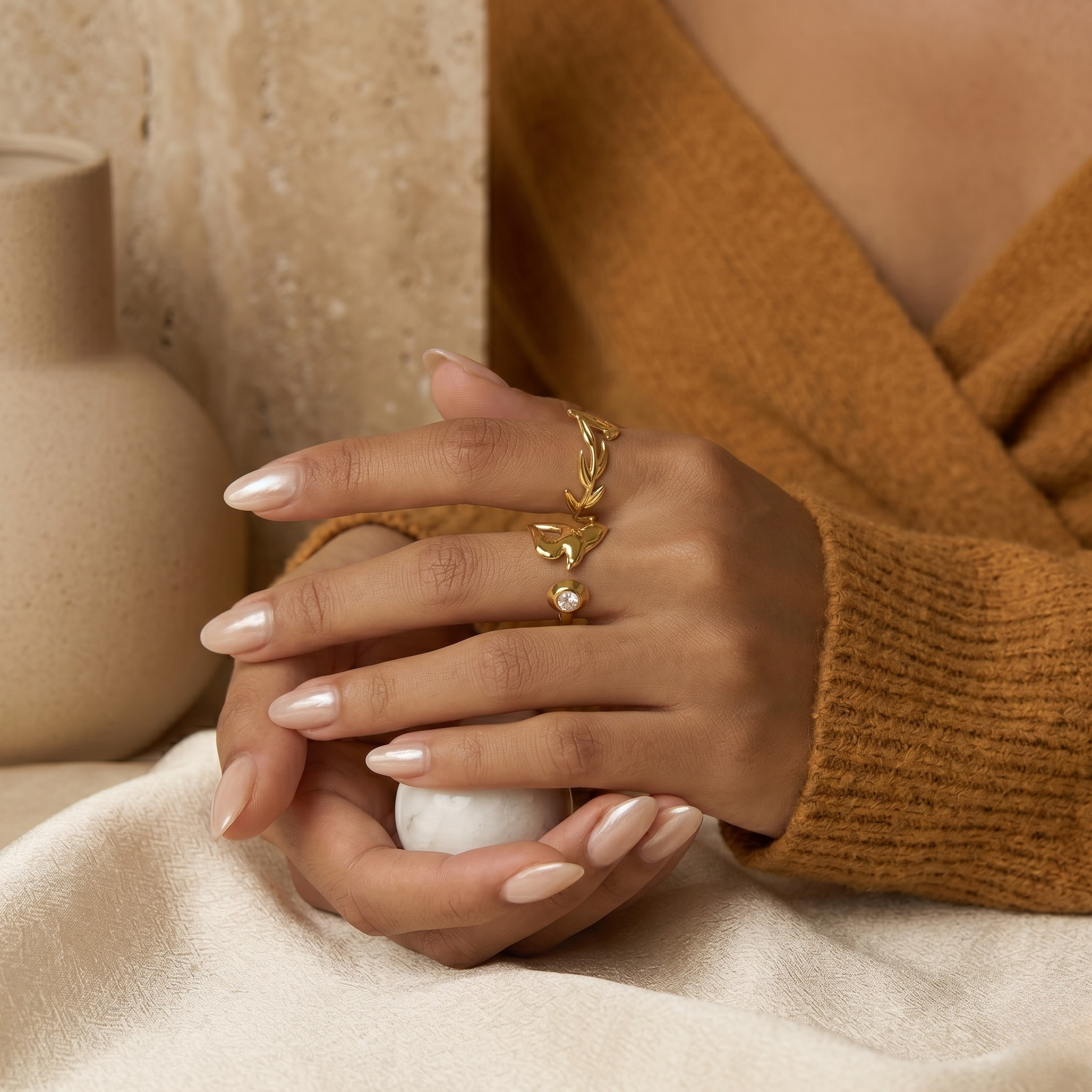 Foliage-inspired gold ring worn on hand, showcasing elegant curves in a serene, neutral setting.