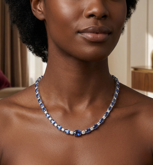 Woman wearing white gold oval blue sapphire and diamond alternating tennis necklace on bare neckline in elegant interior setting - 14K White Gold Lab Sapphire Necklace - J. Collins Jewelry 