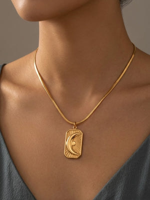 Gold medallion necklace featuring a crescent moon design, worn by a model with a neutral background.