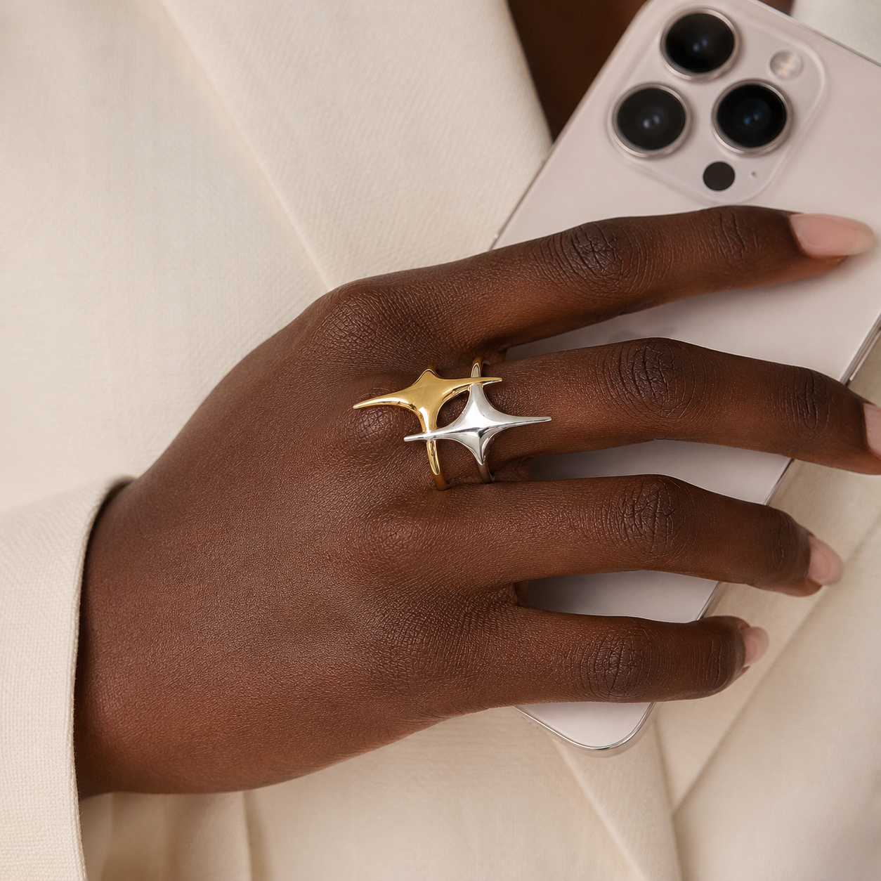 Dual-tone gold and silver Stellar Loop Ring on hand holding a smartphone, showcasing modern design and elegance.