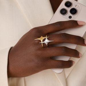 Dual-tone gold and silver Stellar Loop Ring on hand holding a smartphone, showcasing modern design and elegance.