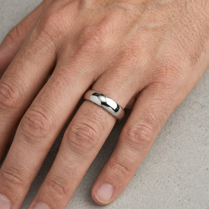 Silver ring on a person's finger against a neutral background