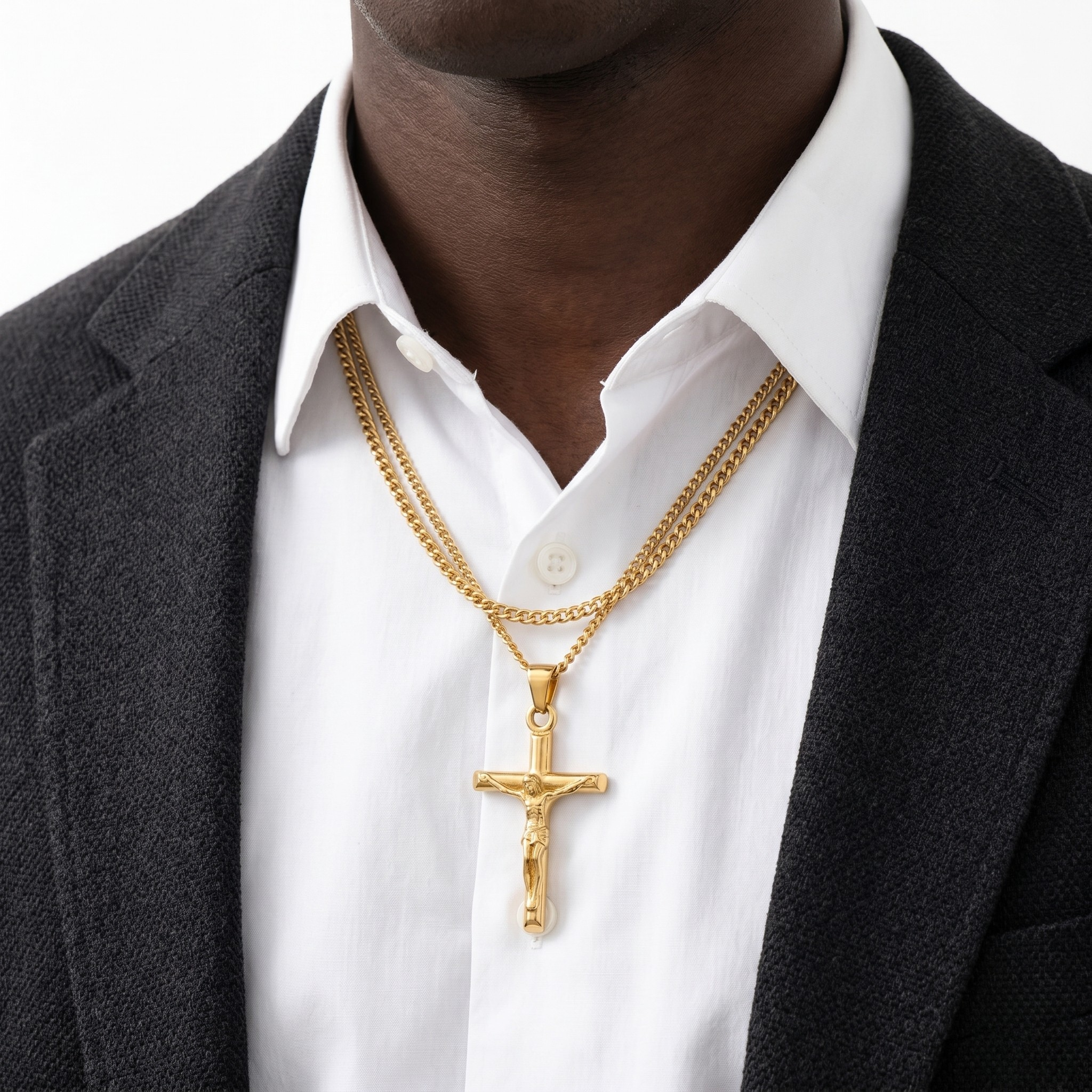Gold cross pendants on layered chains worn over a white shirt and dark suit jacket