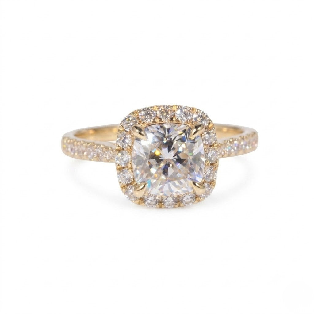 Gold ring featuring a cushion-cut cubic Moissanite center stone surrounded by a halo of round accents shown facing forward on a plain white background by J.Collins
