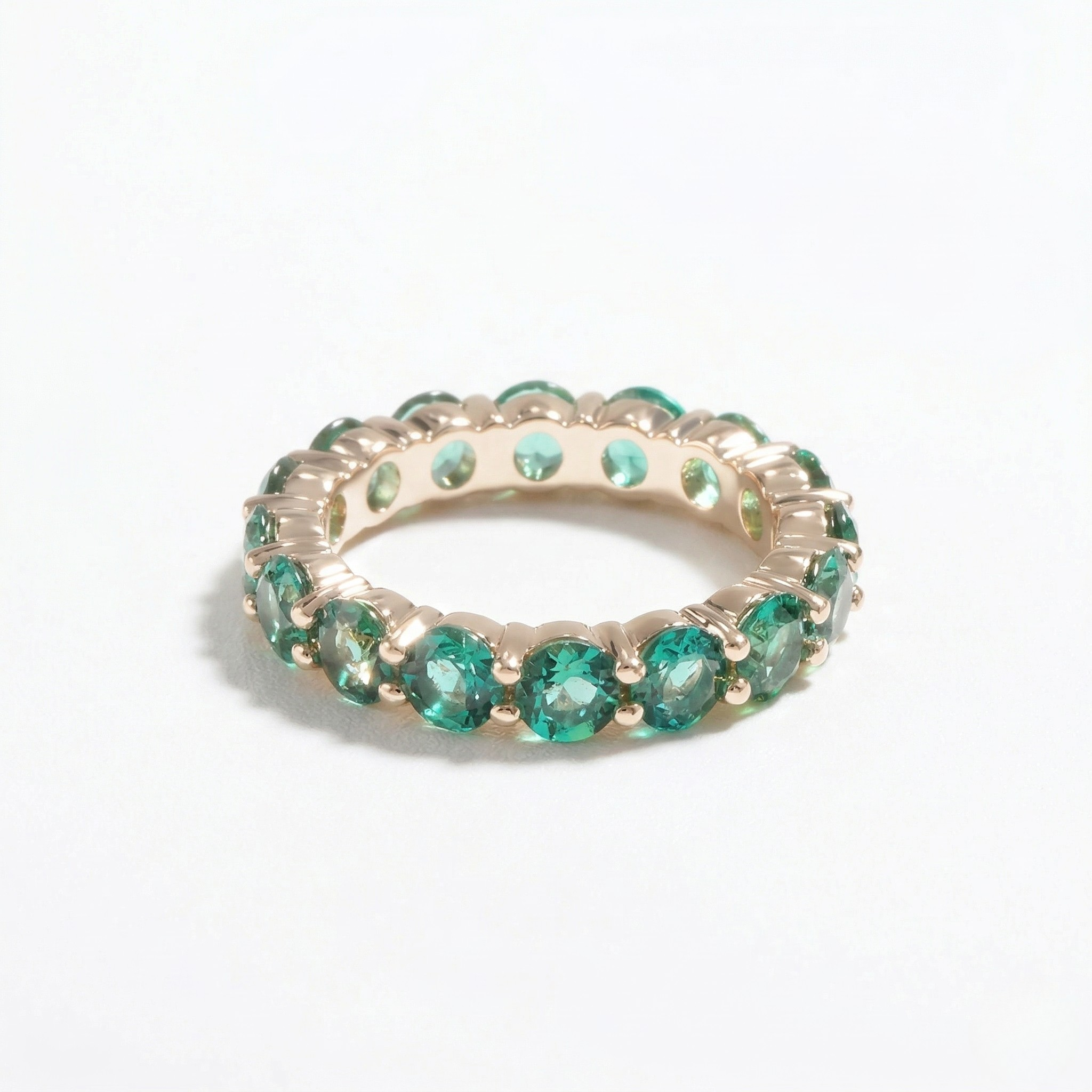 14K yellow gold ring with round lab emeralds, eternity band design, on a white background
