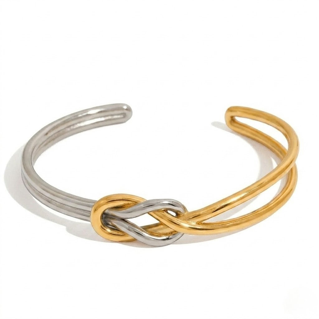 Two-tone ribbon knot cuff bracelet with intertwined gold and silver open bands.