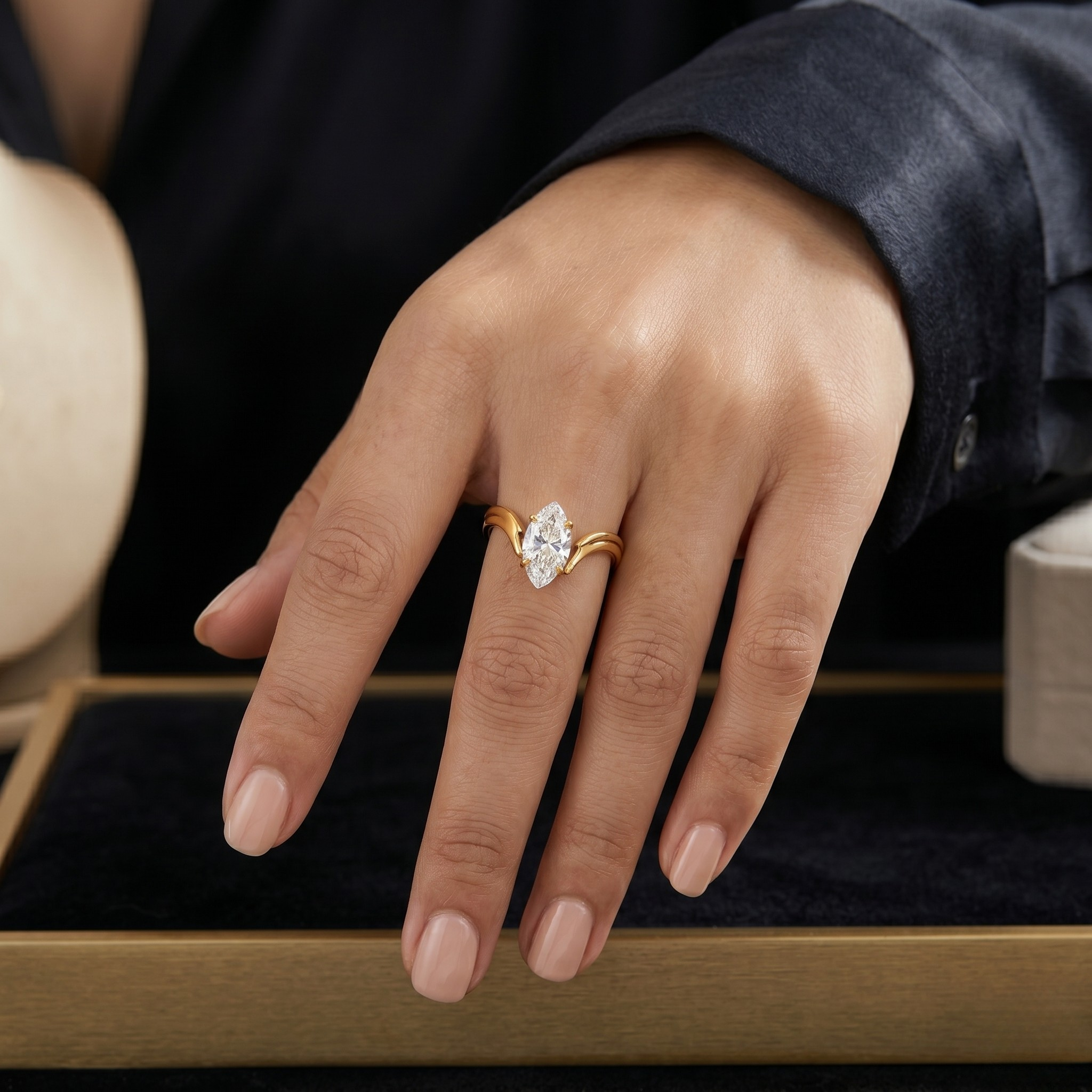 Hand wearing Bold Marquise Ring with gold band and large marquise-cut diamond on dark background.