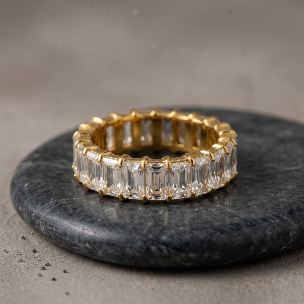 Gold opulent bar ring with rectangular clear stones on a dark circular marble surface